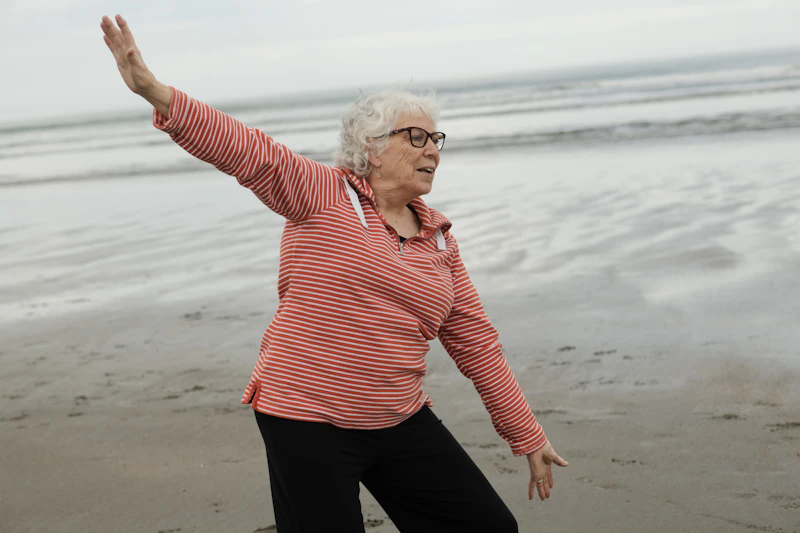 Senior woman practising tai chi on the beach for joint health and gentle movement